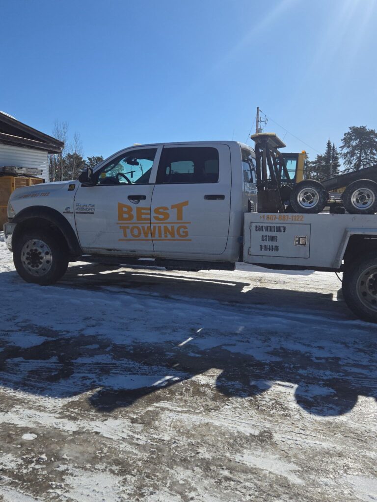 Best Towing flatbed truck parked on a snowy lot in Canada.
