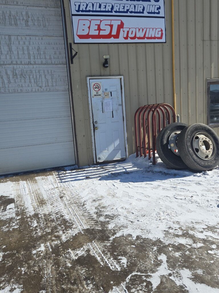 Best Towing facility entrance with truck wheels in snow.